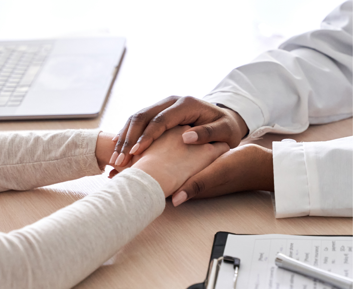 Close up of nurse holding patient's hands on desk.